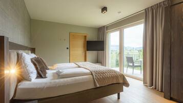 Un dormitorio moderno con una cama grande, un televisor de pantalla plana y un balcón con cortinas.