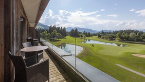 Un balcon doté de meubles en osier, donnant sur un terrain de golf et un étang.