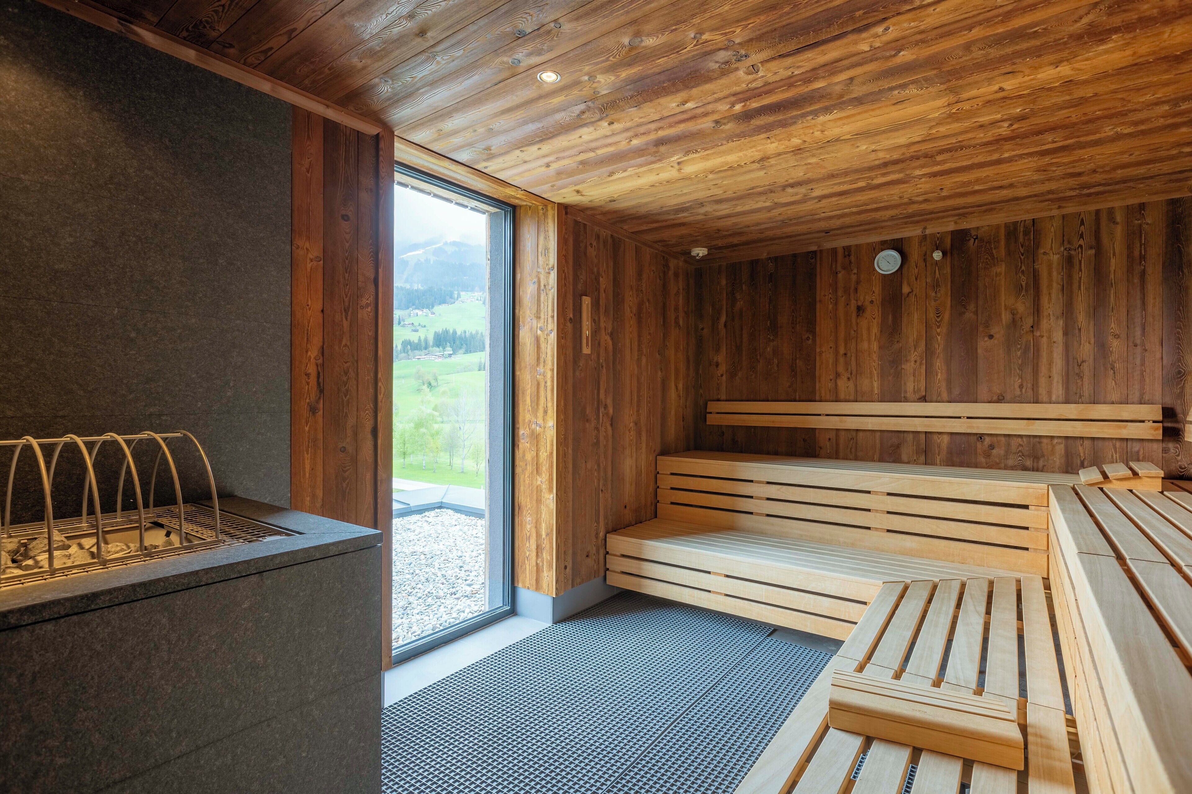 A wooden sauna with benches and a stone wall.