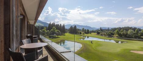 Un balcón con mobiliario de mimbre con vistas a un campo de golf y un estanque.