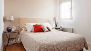 Um quarto com uma cama grande, duas mesas de cabeceira, uma janela e um radiador.