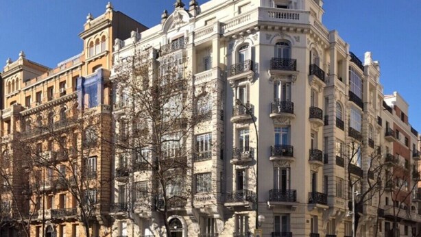 Um edifício de vários andares com arquitetura clássica, com varandas ornamentadas e uma entrada central.