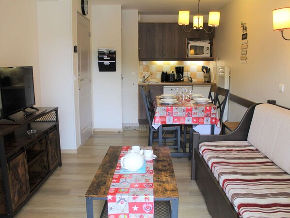 A compact living space with a dining area, kitchenette, and a seating area with a sofa and a table set for a meal.
