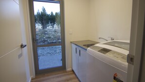A laundry room with a washing machine, a sink, and a door leading to a snowy outdoor area. - Walking distance to lake Ruataniwha (Twizel)