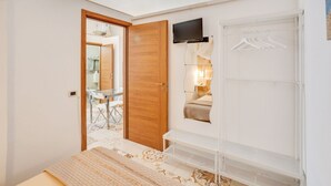 A bedroom with a bed, a TV mounted on the wall, a wardrobe, and a mirror. - GuestHost - Bright apartment equipped with every comfort to accommodate up to 4 people and located in the center of Polignano, in an area equipped with all essential services, easily reachable on foot. The flat is 400 meters from the lively Piazza Vittor (Polignano a Mare)