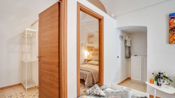 A room with a bed, a table with breakfast, a white wardrobe, and a bathroom visible through an open door. - GuestHost - Bright apartment equipped with every comfort to accommodate up to 4 people and located in the center of Polignano, in an area equipped with all essential services, easily reachable on foot. The flat is 400 meters from the lively Piazza Vittor (Polignano a Mare)