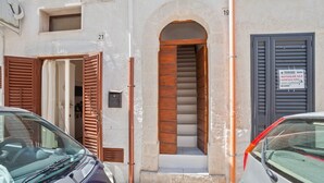 Un edificio con una escalera que conduce a una entrada, número 19, y un cartel que indica un comercio a la derecha.