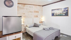 Un dormitorio con cama, un reloj de pared, un cuadro enmarcado y un refrigerador.