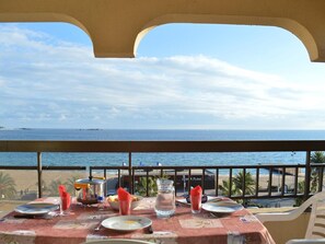 Een tafel gedekt voor twee personen, met uitzicht op zee en een strand.