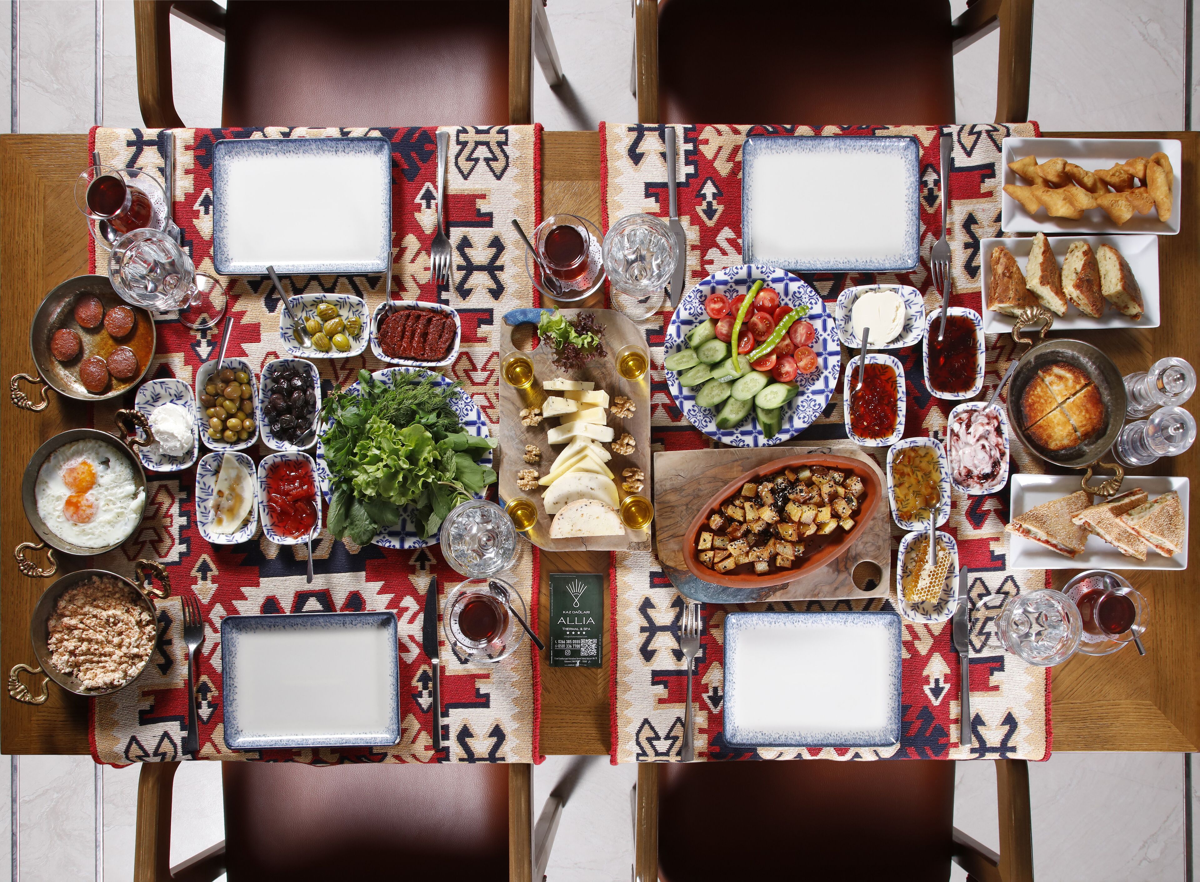 A table set for a meal with various dishes, including salads, meats, and bread, arranged on a patterned tablecloth.