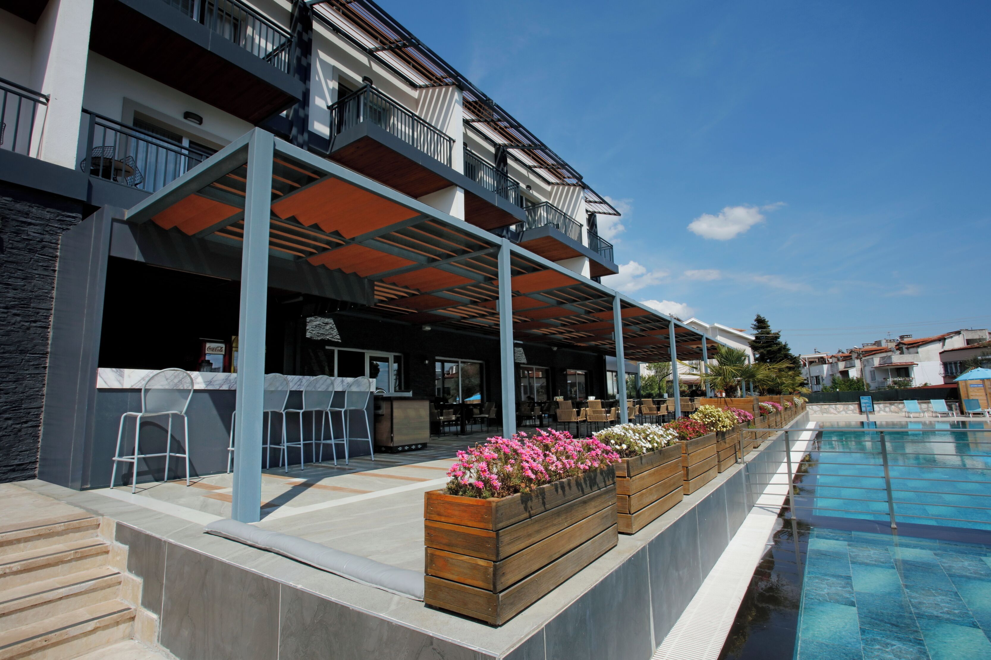 A modern hotel with outdoor seating, a pool, and a covered patio area.