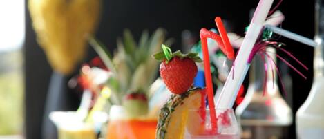 Eine Bar mit einem Getränk, verziert mit Erdbeere und Ananas, und mehreren Trinkhalmen.