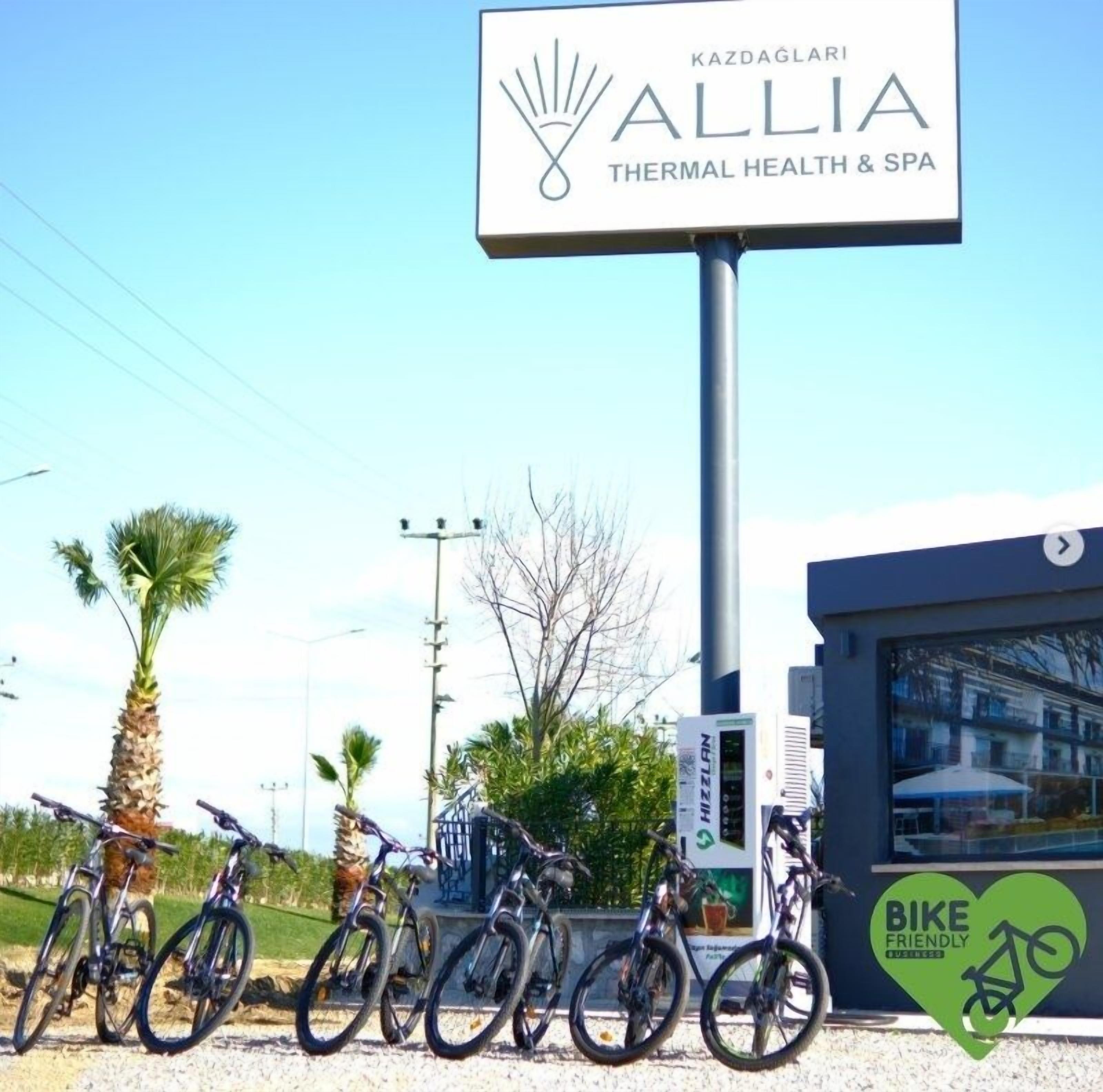Una señalización para 'ALLIA THERMAL HEALTH & SPA' con bicicletas estacionadas al frente.