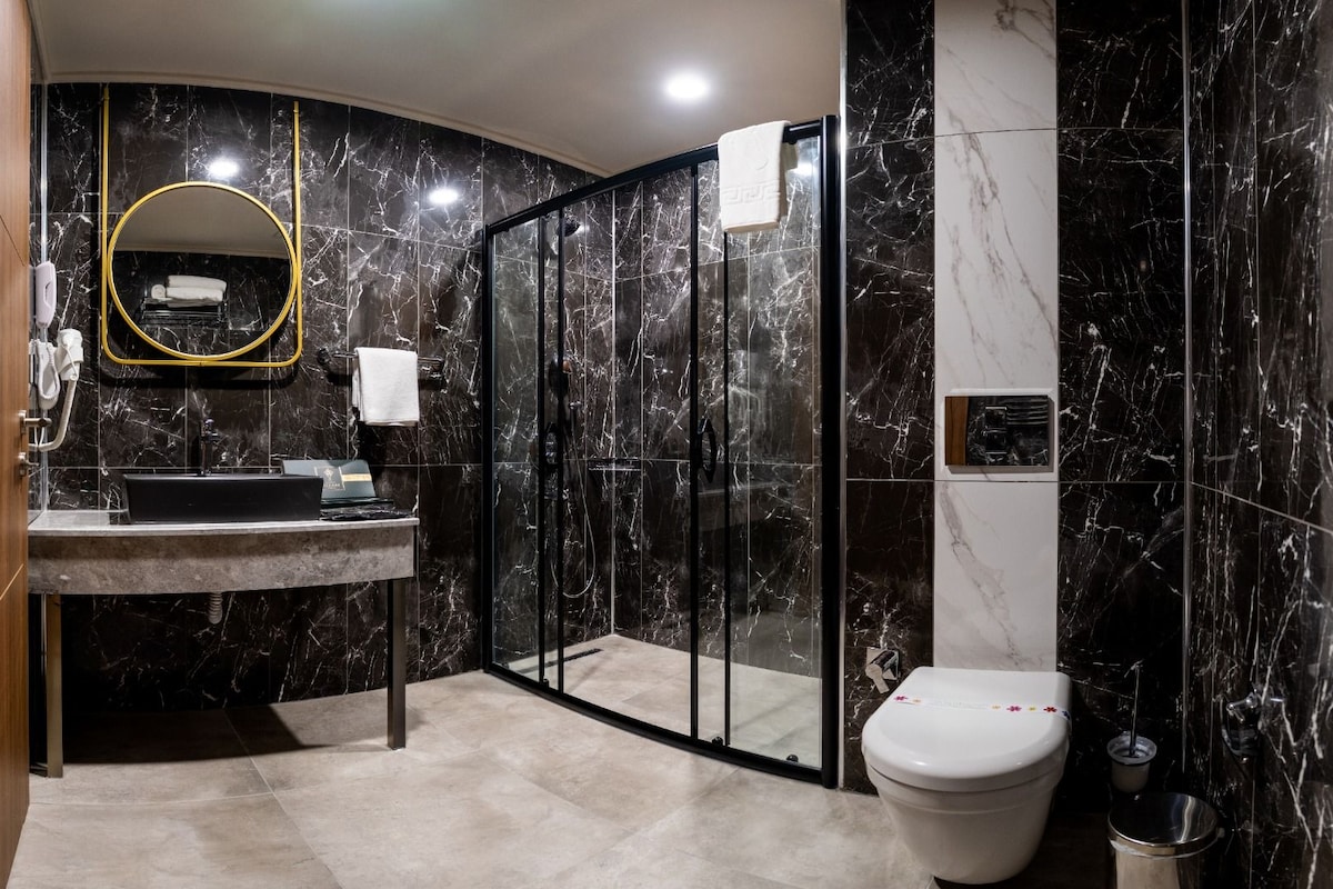 A modern bathroom with a marble vanity, a glass shower enclosure, and a toilet.