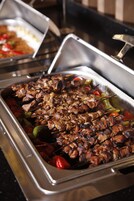 Buffet com carne e legumes espetados.