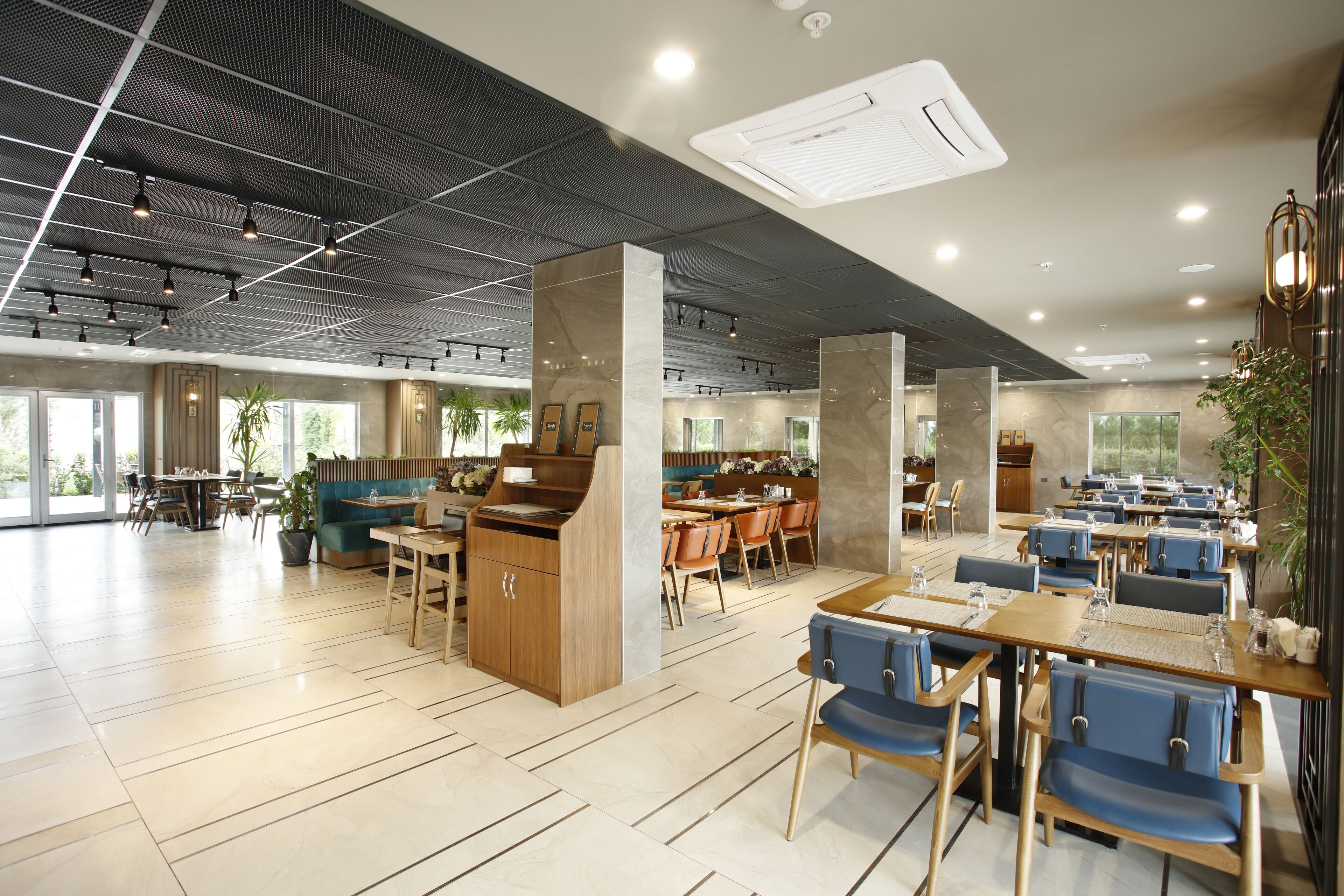 A spacious restaurant with high ceilings, modern lighting, and a mix of seating arrangements including tables and booths.