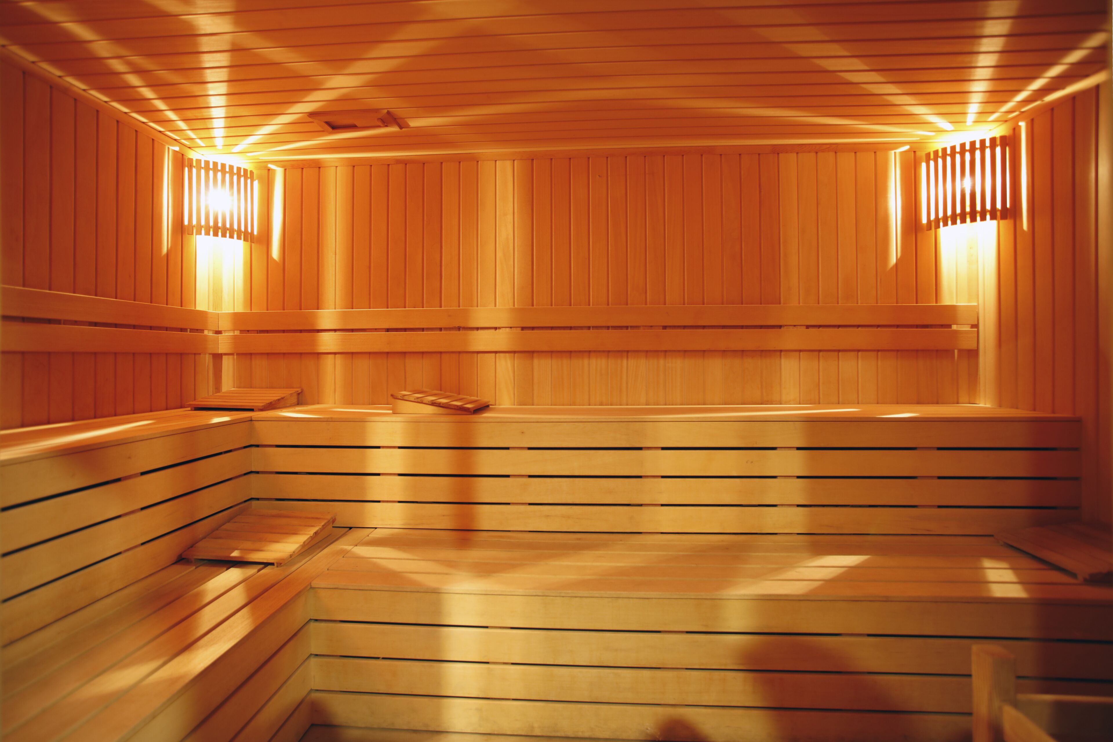 Una sauna con bancos de madera y paredes con listones, que incluye luces empotradas.