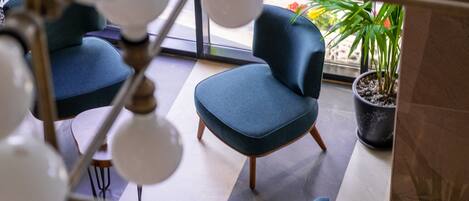 A modern interior with a blue sofa, a potted plant, and a hanging light fixture.