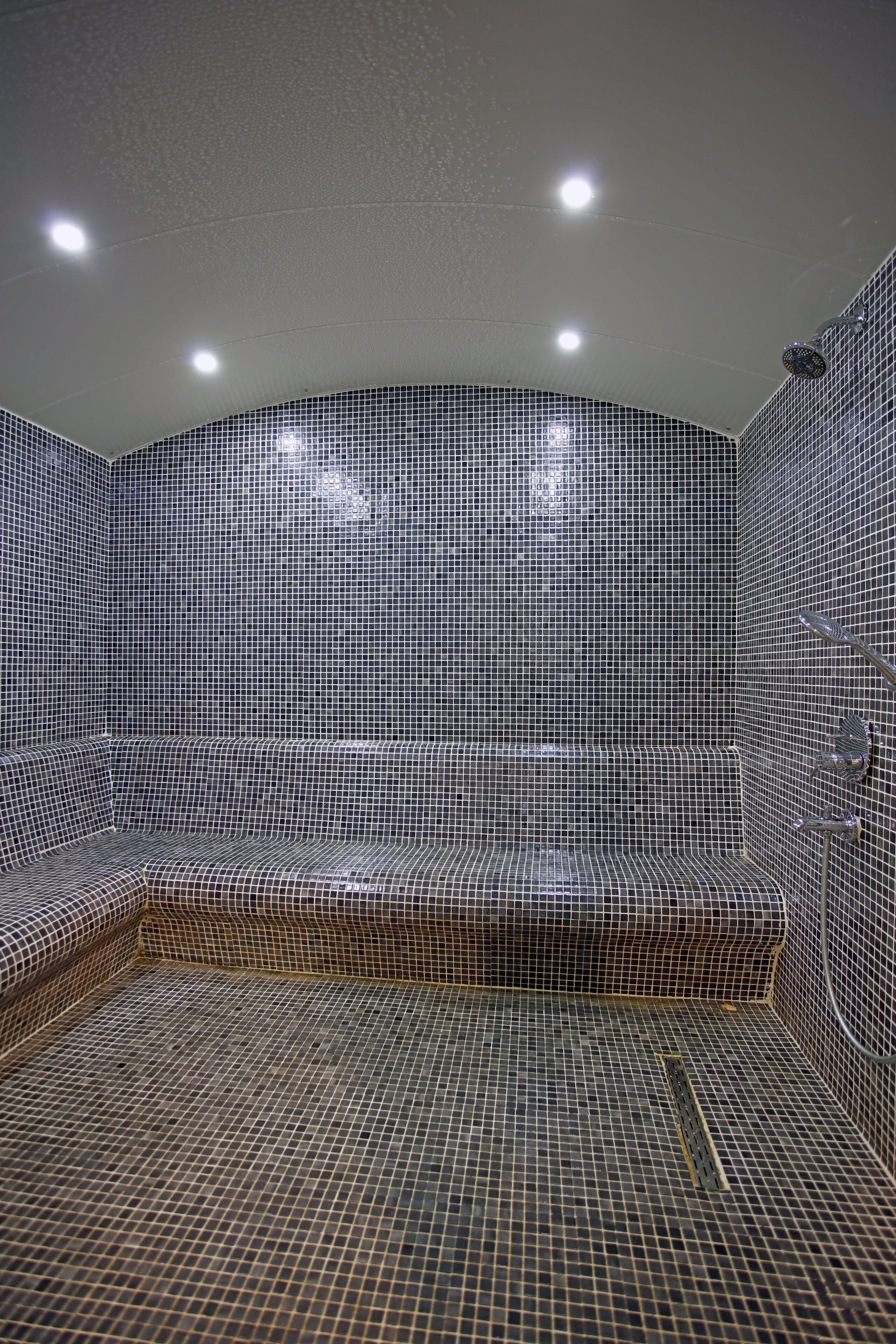 A tiled room with a bench and a shower area.