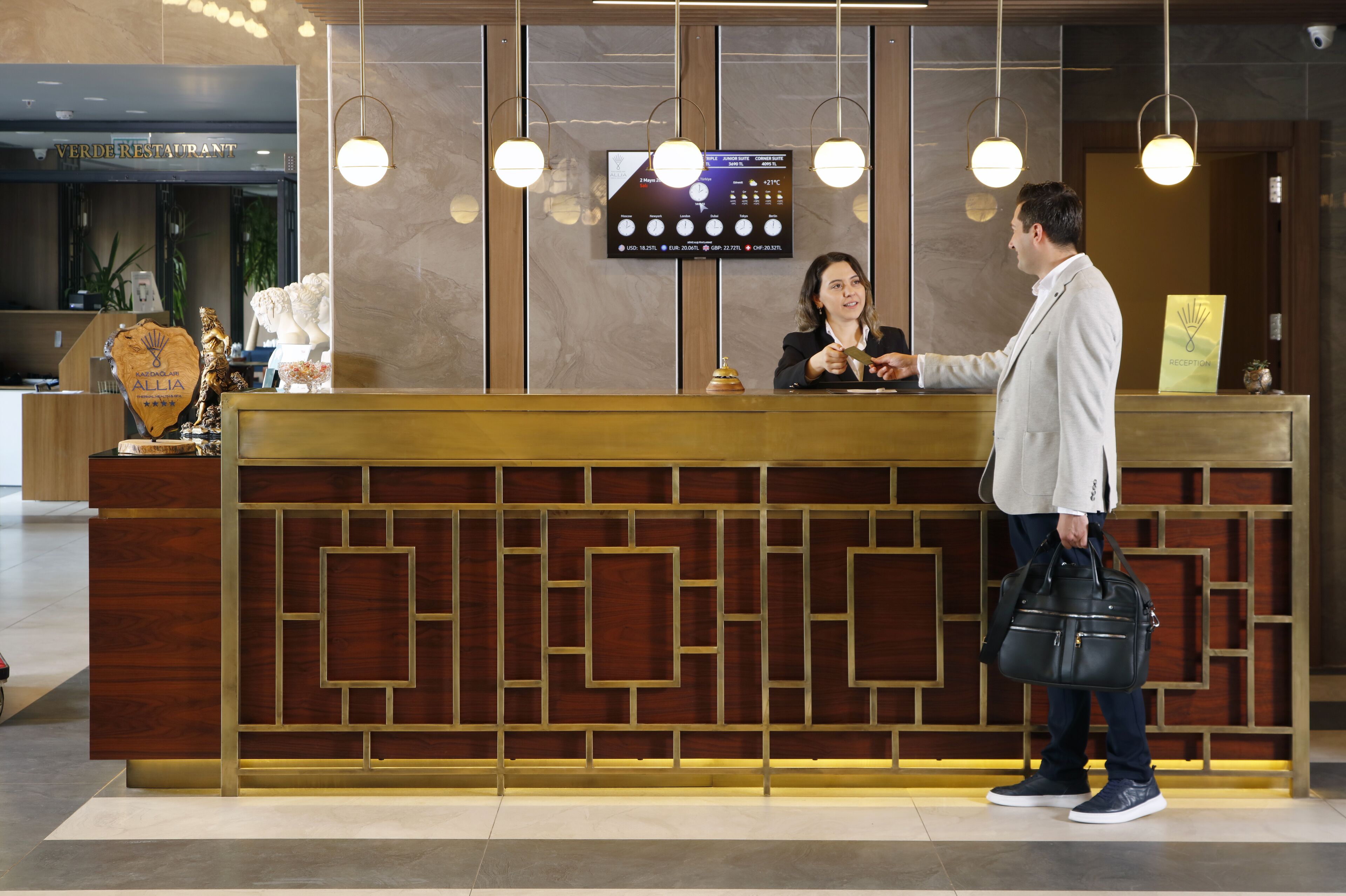 A hotel reception desk with a digital screen displaying room rates and amenities.