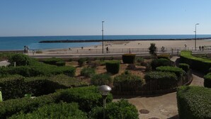 Een kustpromenade met een strand, een promenade met een hek en een heldere lucht.