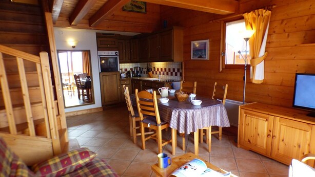 Acogedor interior de cabaña con comedor, cocina y sala de estar con sofá.