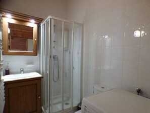 Un bagno con doccia vetro, mobile lavabo in legno e lavandino bianco.