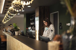 Uma receção com design moderno, incluindo uma luminária pendente singular e um vaso com planta.