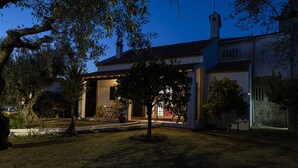 Et hus med en overdækket veranda, en have og et træ foran.