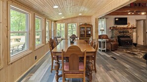 Un comedor amplio con una larga mesa de madera y sillas, rodeado de grandes ventanales con vistas al exterior.