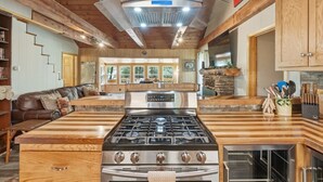 Una cocina con una isla central, armarios de madera y una chimenea de piedra.