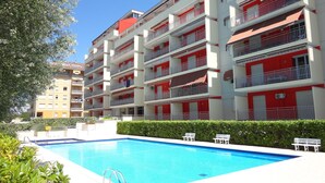 Un hotel de varios pisos con piscina, balcones y un cielo azul despejado.