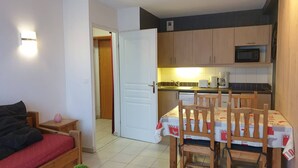 A compact living space with a kitchenette, a dining area with a table and chairs, a bed, and a small potted plant. - Cozy apartment with pool, sleeps 4, Les Orres 1800 (Les Orres)