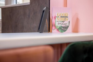 Ein Schreibtisch mit einem Computermonitor und einer Karte mit dem Aufdruck 'GOOD VIBES only' und einem Blatt-Design.