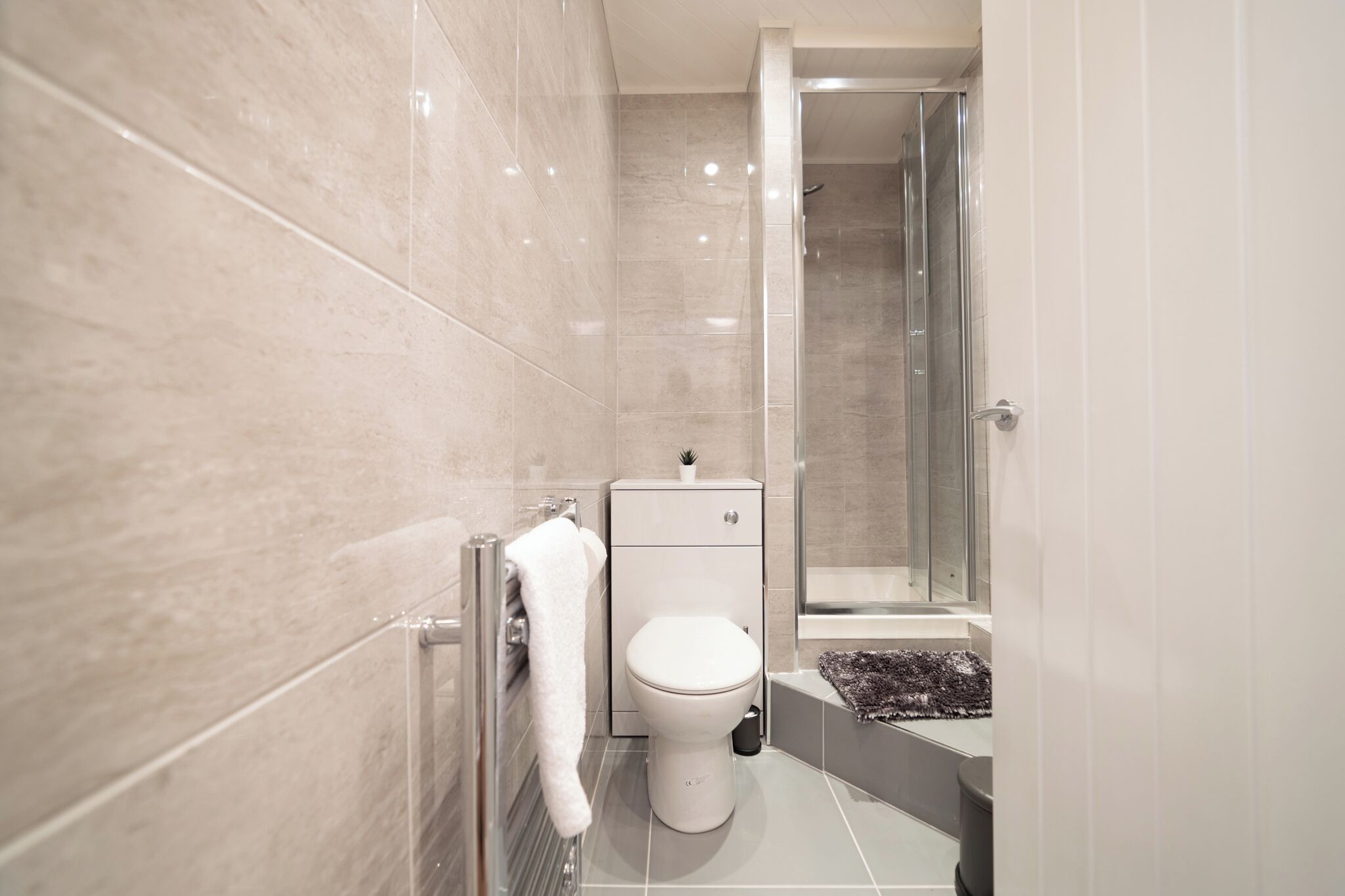 Een moderne badkamer met toilet, douche en een klein kastje.