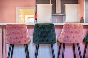 Drei gepolsterte Stühle mit schwarzen Beinen und eine weiße Arbeitsplatte im Hintergrund.