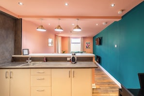 Una cocina moderna con una isla central, iluminación colgante y vista a un comedor.