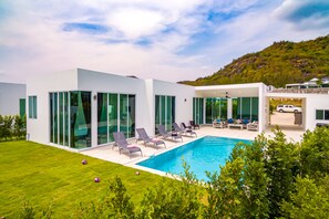 Una casa moderna con piscina, amplios ventanales y un césped cuidado.