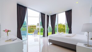 Quarto de hotel moderno com uma cama grande, uma escrivaninha e vista para o exterior.