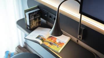 Uma mesa com uma luminária, um livro aberto e uma caixa de livros.