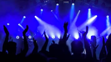 A concert with blue stage lighting and a crowd raising their hands.