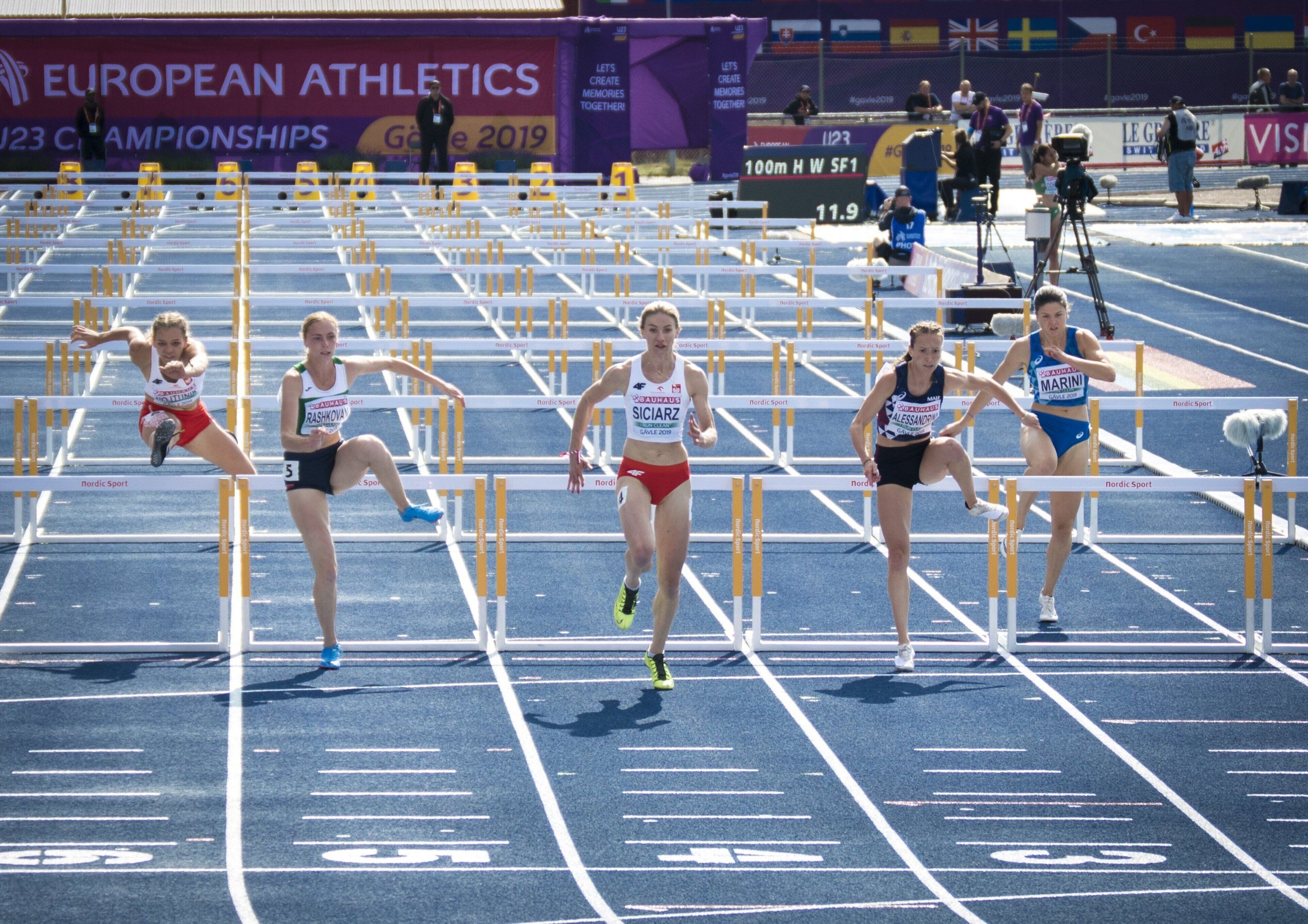 A track and field event with athletes competing in hurdles.