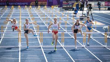 A track and field event with athletes competing in hurdles.