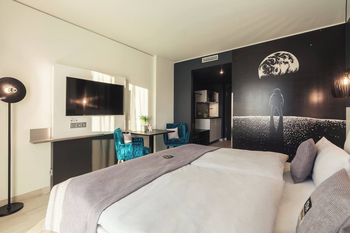 A modern hotel room with a large bed, a desk, and a TV.