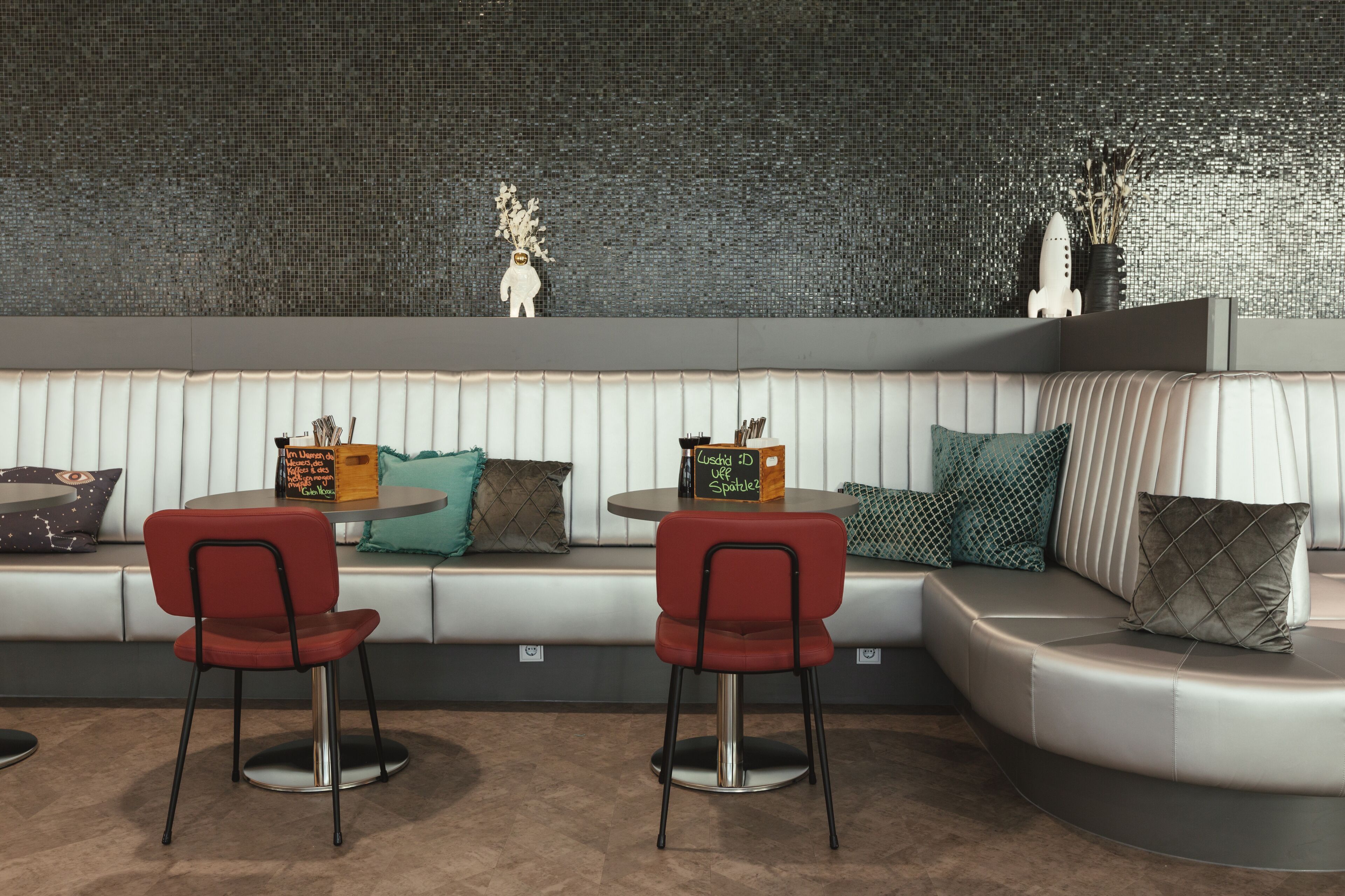 A modern seating area with a curved sofa, two red chairs, and a small table.
