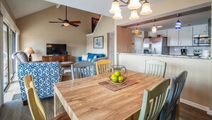 Una cocina moderna con electrodomésticos de acero inoxidable, un comedor con mesa y sillas de madera y un ventilador de techo.