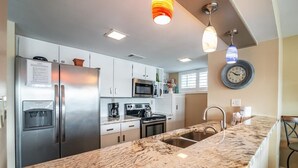 Una cocina moderna con electrodomésticos de acero inoxidable, encimera de mármol e iluminación colgante.