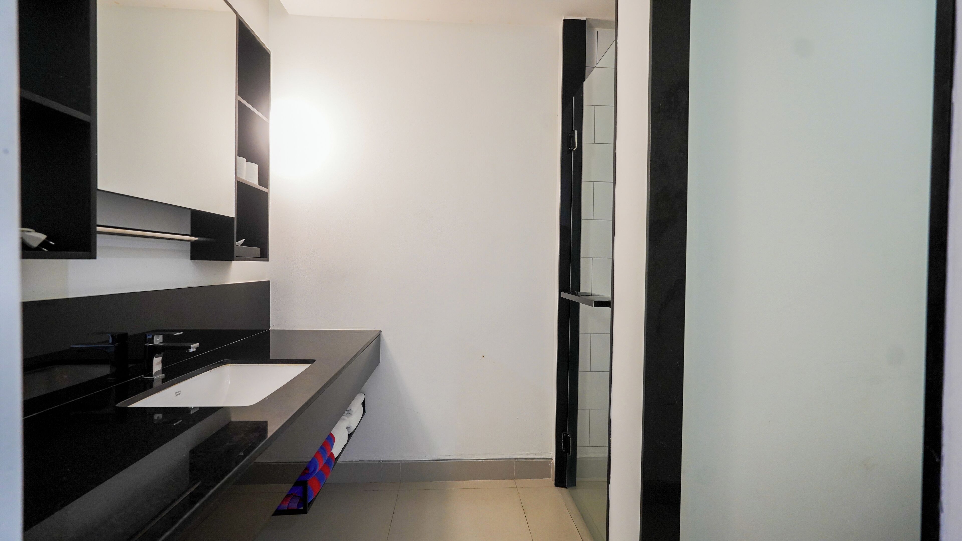 A modern bathroom with a black vanity, a white sink, and a large mirror.