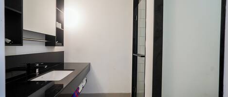 A modern bathroom with a black vanity, a white sink, and a large mirror.