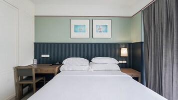 A hotel room with a bed, two bedside tables, a desk, and a lamp.